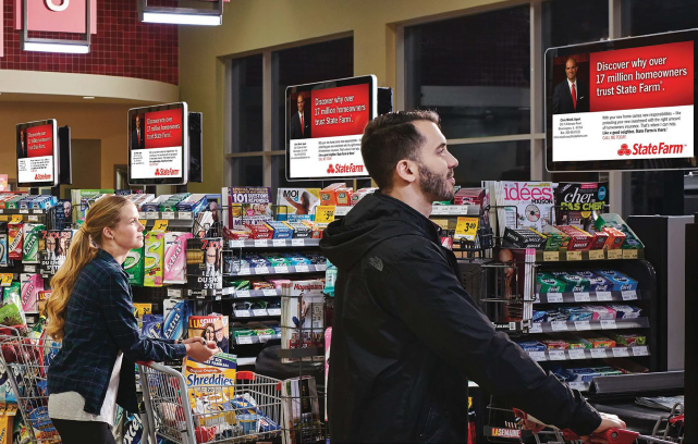 Two shoppers looking at digital signage in a grocery store.